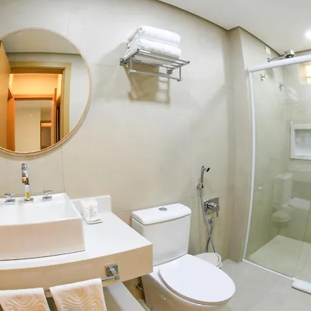 Costao Do Santinho Resort All Inclusive Florianópolis Habitación foto This is a photo of a modern and bright bathroom, likely in a hotel or high-end accommodation.

**Key features visible in the image include:**

*   **Vanity Area:** On the left, there is a white, modern sink basin set into a white countertop. A large,