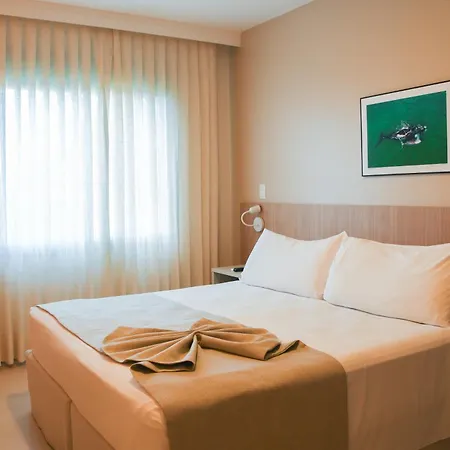 Costao Do Santinho Resort All Inclusive Florianópolis Habitación foto This is an image of a bright and modern hotel room. The focal point is a large, comfortable bed, neatly made with white linens and topped with several pillows. A beige or light brown throw blanket is casually draped across the foot of the bed.

The r