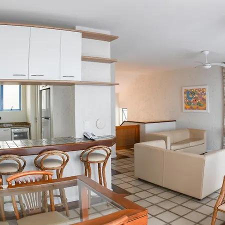 Costao Do Santinho Resort All Inclusive Florianópolis Habitación foto This image depicts a bright, modern, and open-plan living space that combines a kitchen area with a lounge or living room.

**Kitchen Area:**
On the left side of the frame, there is a contemporary kitchen featuring sleek, white, upper cabinetry. Belo