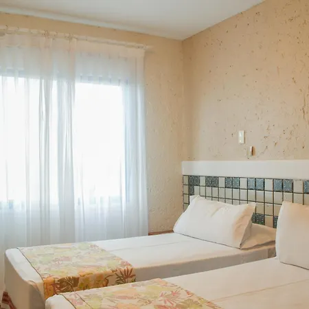 Costao Do Santinho Resort All Inclusive Florianópolis Habitación foto This is a photo of a bright and simple hotel or guest room.

**Key features of the image:**

*   **Bed:** There are at least two single beds pushed together or placed close to each other, both covered with white bedding. The lower part of the beds fe
