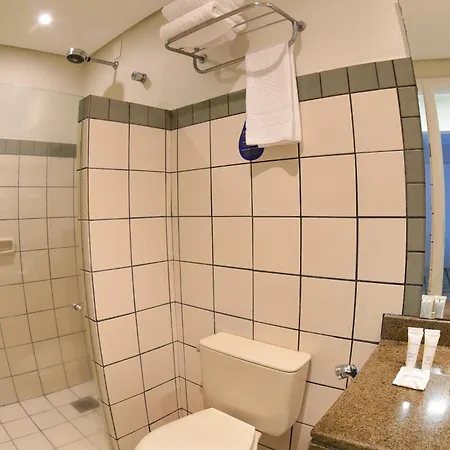 Costao Do Santinho Resort All Inclusive Florianópolis Habitación foto This is a photo of a modern, clean, and well-tiled bathroom.

The main focus of the image is a shower/toilet area. The walls are extensively covered in large, square, off-white or cream-colored tiles, which are outlined with thin black grout lines, c